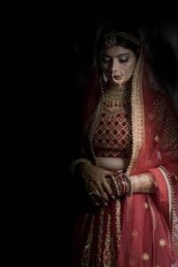 Elegant Indian bride in traditional red lehenga during a wedding ceremony.